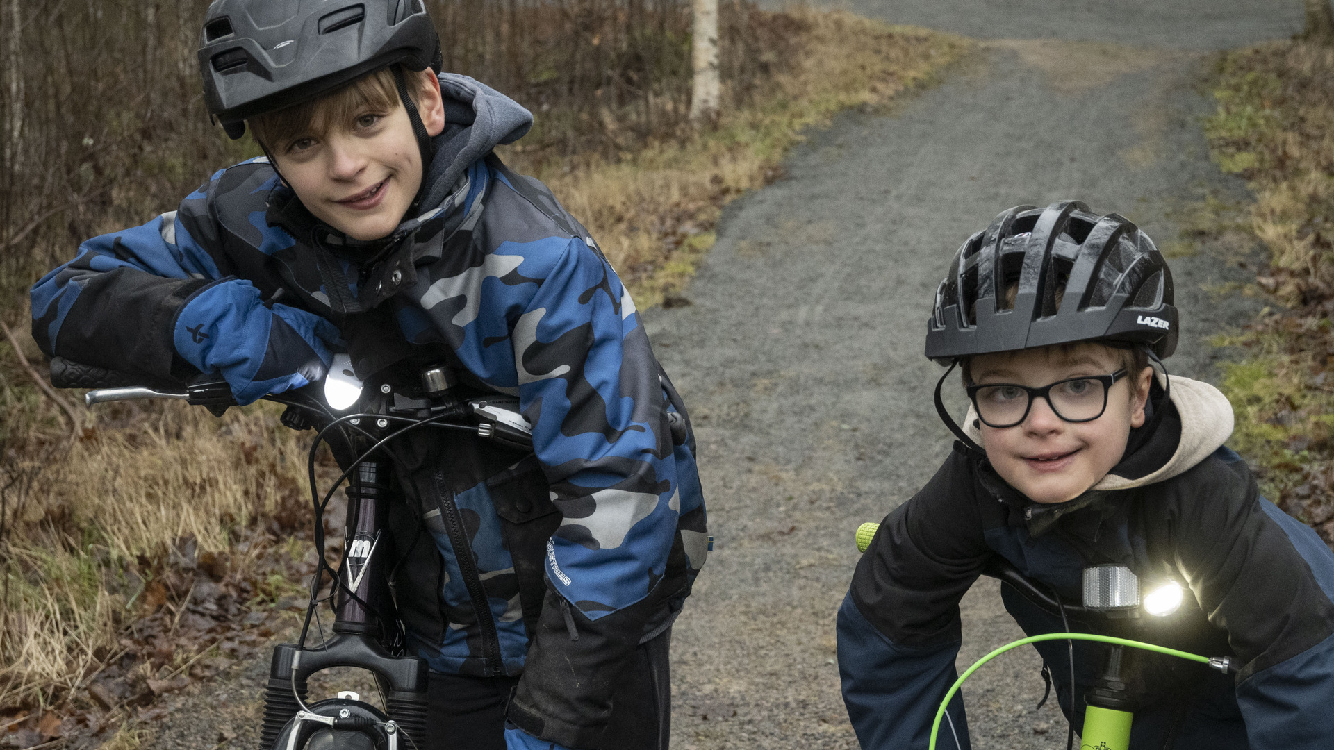 Två pojkar hänger över styret på sina cyklar.