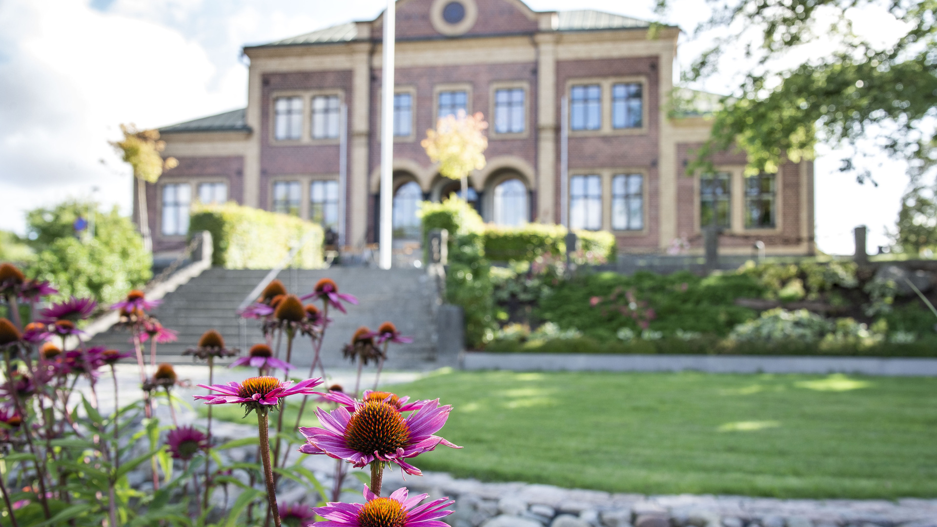 Bild på Sävsjö kommuns kommunhus med blommor och grönska i förgrunden