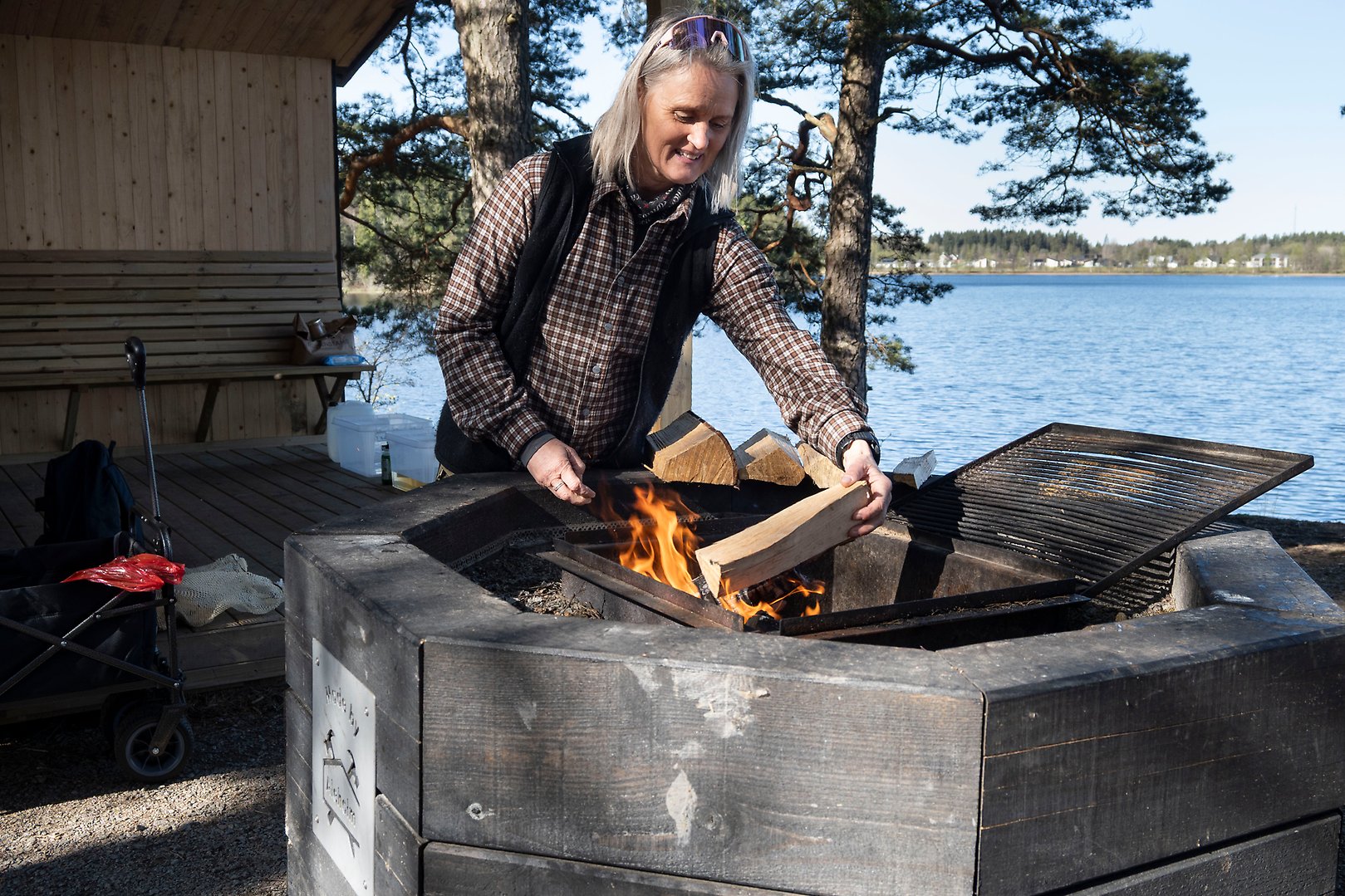 Kvinna lägger på ved på grillplats